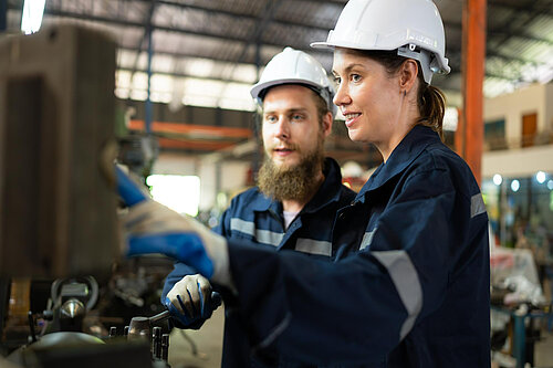 Two people using a machine.